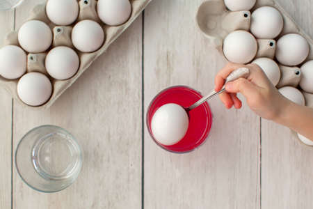 Easter preparation. Little girl paints eggs. Two dozen white eggs on wooden background. Inspiration....