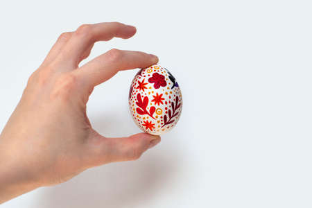Easter egg with watercolor floral print. In hand. Handmade painting. On isolated background.の写真素材