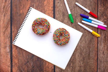 Classic chocolate donut with sprinkles on white paper. For your text.