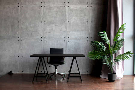 Desktop in the office. Dark concrete walls. Tropical flower in a pot. Table.