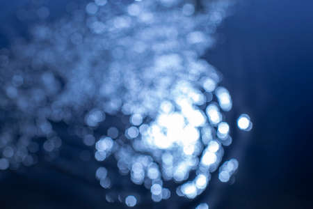 Sun glare on a blue background. White sparkling abstract. Festive concept. Bokeh. Classic blue. の写真素材