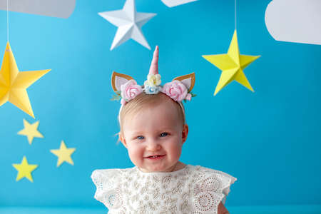 One year old baby celebrates birthday. Photo zone. Cute dress in white color. She touches a paper yellow star. Portrait.の写真素材