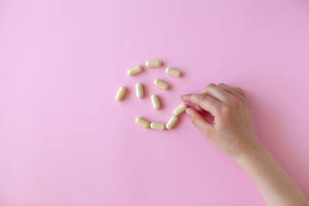 Pills in a hands on pink background. Medicine concept. Funny face.の写真素材