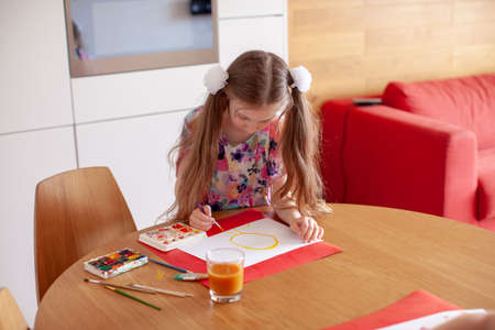 7 years old girl painting with  in the kitchen. Home interior.
