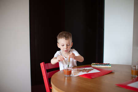Three year old boy paint with  at home. Kitchen interior.の写真素材
