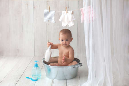 One year old baby takes a bath. Bathed in a basin with rubber ducks.の写真素材