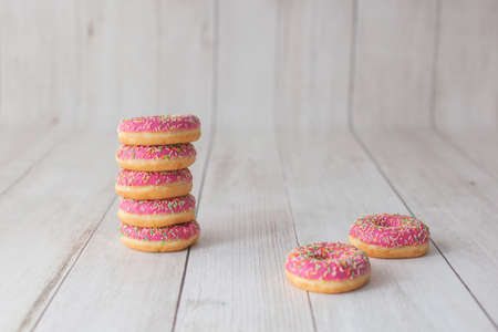 Five strawberry donut on wooden background. With colorful sprinkles.の写真素材