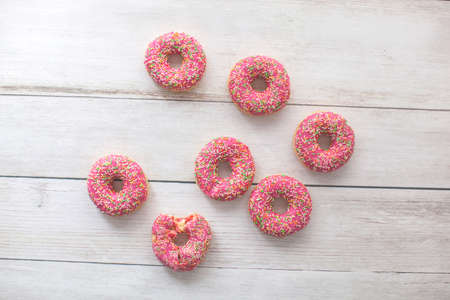 Seven strawberry donut on wooden background. With colorful sprinkles.の写真素材