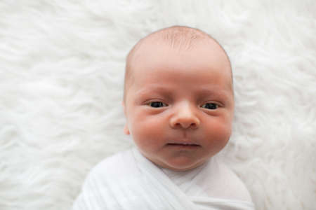 Newborn baby boy. Portrait of a little boy on white fur. Props. Close-up.の写真素材