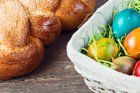 Easter wicker basket with colored eggs and Easter bread on grey wooden board.の写真素材