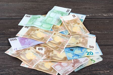 Pile of money on grey wooden board.
