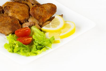 Pork fillet steak with cherry tomatoes, lemon and a lettuce in white dish on white background.の写真素材