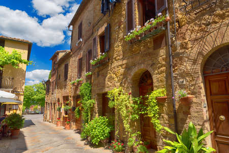 PIENZA, ITALY - MAY 26, 2017: Beautiful narrow street with sunlight and flowers in the small magical and old village of Pienza, Val D'Orcia Tuscany, Italy.のeditorial素材