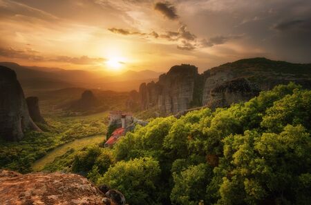Monastery Meteora Greece. Stunning spring panoramic landscape at sunset. View at mountains and green forest against epic sky with clouds.の写真素材