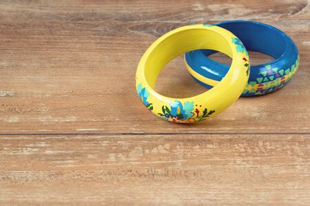 Close-up image of an yellow and blue bracelets on brown wooden background.