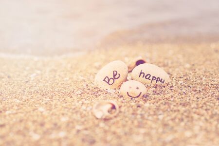 Beautiful sunlight with clean sea sand and the waves are blowing on the beach. Small rocks with inscription, near the water.の写真素材