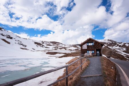 Landscape view from Hochtor tunnel on the Grossglockner high alpine road. Looking towards Heiligenblut in Carinthia with blue sky, mountains clouds and snow and the Grossglockner high alpine road.の写真素材