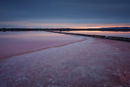 Beautiful landscape on sunset with a salt farm. Magnificent colors, dark clouds. Burgas, Bulgaria.の写真素材
