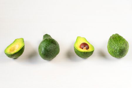 Isolated avocado. Whole avocado fruits and two halves in a row isolated on white backgroundの写真素材