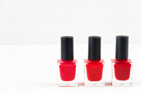 Close-up image of three Red nail polish bottles on white wooden background.の写真素材