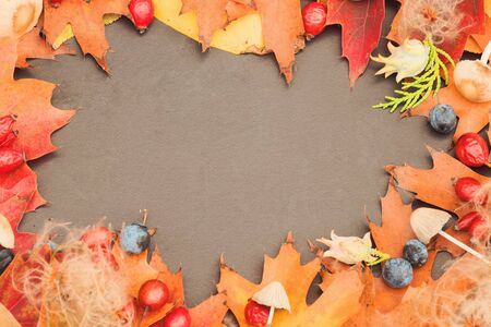 Autumn background with beautiful leaves, rosehips, walnuts, forest mushrooms on an old dark table. Mockup for seasonal offers and a holiday card.の写真素材