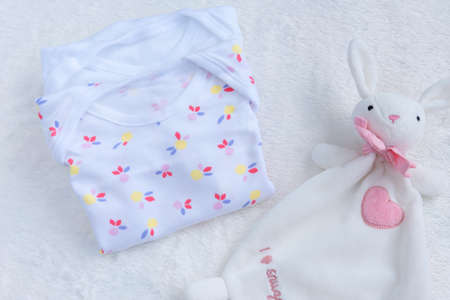 Bodysuits for baby girl and a toy on a white fur carpet. Newborn Baby Concept. Baby Girl Clothes Set.の写真素材