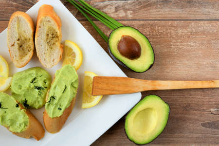 Healthy breakfast snack . Close up of baguette slices with fresh homemade avocado pasta-cream. Avocado,eggs,lemon juice,olive oil,salt and pepper . Fresh slices of lemon and avocado as a decoration.の写真素材