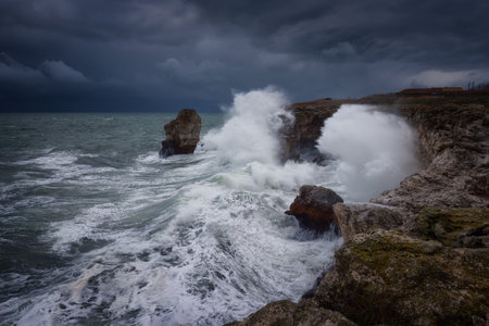 Dramatic nature background - big waves and dark rock in stormy sea, stormy weather. Dramatic scene. Contrasting colors.Beautiful natural landscape, seascape at Tyulenovo, Bulgaria.の写真素材