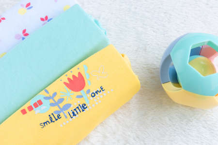 Baby Mockup. Bodysuits for baby girl And Rattle Toy On A White Fur Carpet. Newborn Baby Concept. Baby Girl Clothes Set.の写真素材