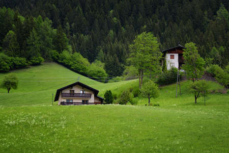 Idyllic landscape in the Alps in springtime with traditional mountain chalet and fresh green mountain pastures with blooming flowers on a beautiful sunny day. Austria, Europe.の写真素材
