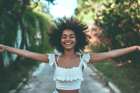 Smiling young dancer dancing with arms outstretched on footpathの素材