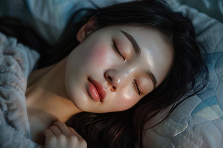 sleeping young asian woman lies in bed with eyes closedの素材