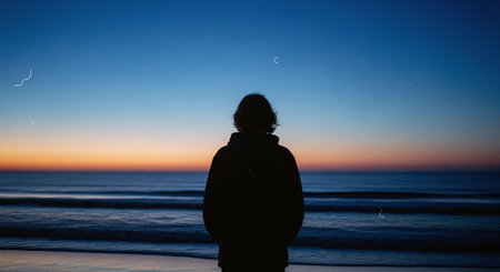 Silhouette of a woman looking at the sea at sunset.の素材