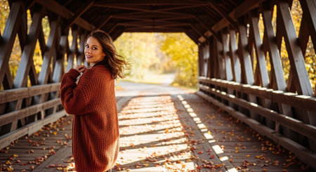 Portrait of a young beautiful woman in a red sweater on the bridge in autumn.の素材
