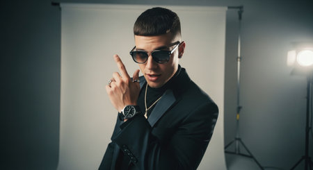 Handsome young man in a black suit and sunglasses in the studioの素材