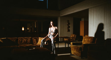 Beautiful young woman in a dark room with a large window.の素材