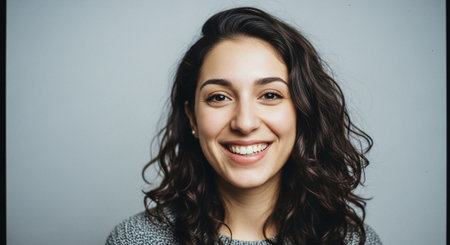 A smiling woman with curly hair, wearing a sweater, against a plain backgroundの素材