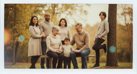 Portrait of happy family sitting on bench in park during autumn seasonの素材