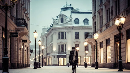 Lone Traveler Walking Through Elegant European Street in Winter Snowの素材