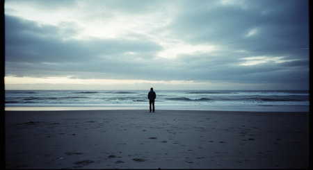 A man standing on the beach in the evening with the sea in the backgroundの素材