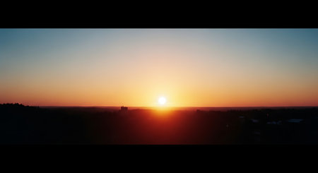 A serene sunset over a vast landscape with a clear skyの素材