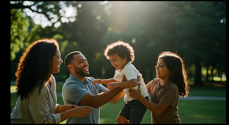 A happy family of four playing together in a park on a sunny dayの素材