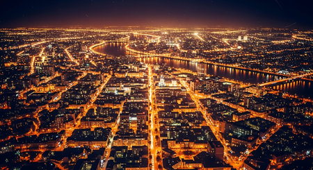 Aerial night view of a city with brightly lit streets, buildings, and a winding river. The scene is vibrant with city lights and reflections on the water.の素材