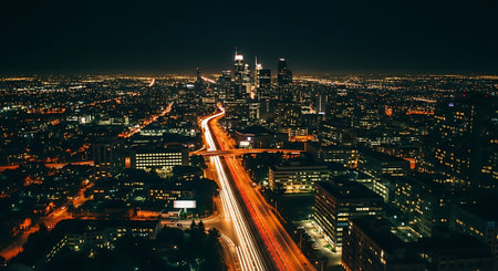 Aerial view of a city at night with a busy highway and skyscrapersの素材