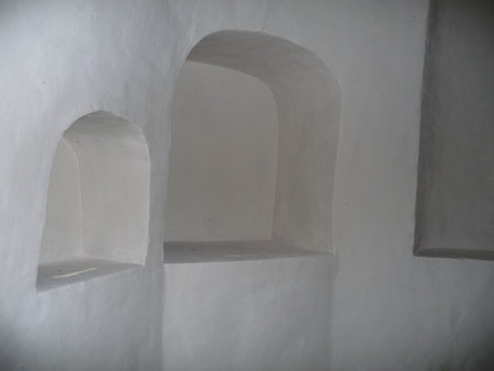 A close-up shot of two empty, white, arched wall niches in an ancient or minimalist architectural setting.の写真素材