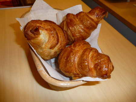 Crispy croissants in a basket on a wooden tableの写真素材