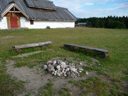 The old wooden house in the village in Norway. The benches around the hearth made of stones.の写真素材