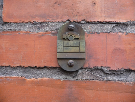 Weathered, vintage metal plaque mounted on a rough brick wall with thick mortar joints.の写真素材