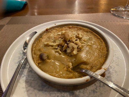 A bowl of baked halva with walnuts on a table in a restaurantの写真素材