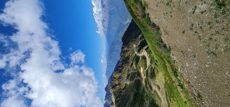 Stunning summer landscape with green mountain slopes, hiking trails, and a cable car line in the...